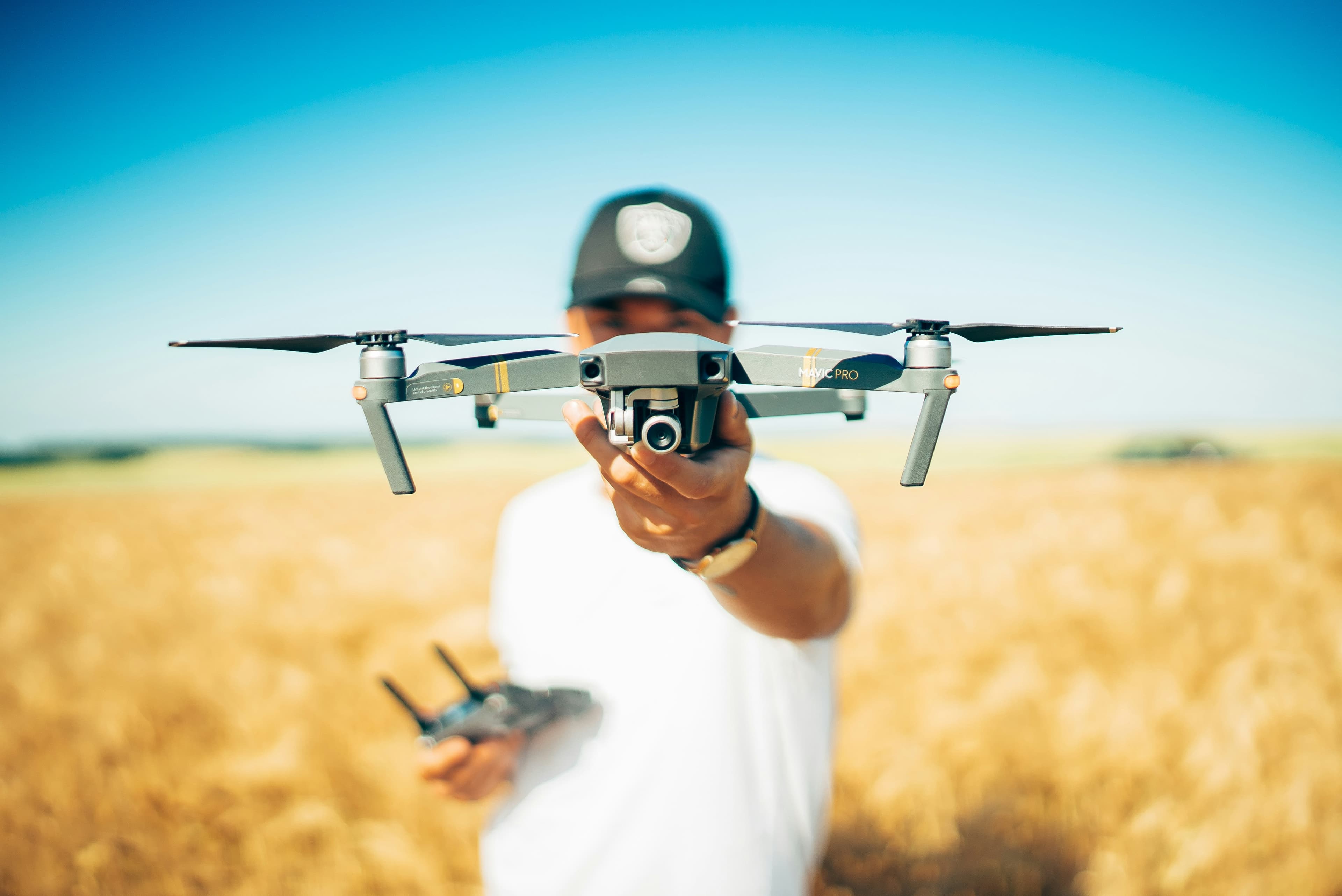 Télépilote présentant son drone DJI Mavic Pro, télécommande en main, au-dessus d'un champ de blé — illustration de la réglementation ANAC drone Bénin