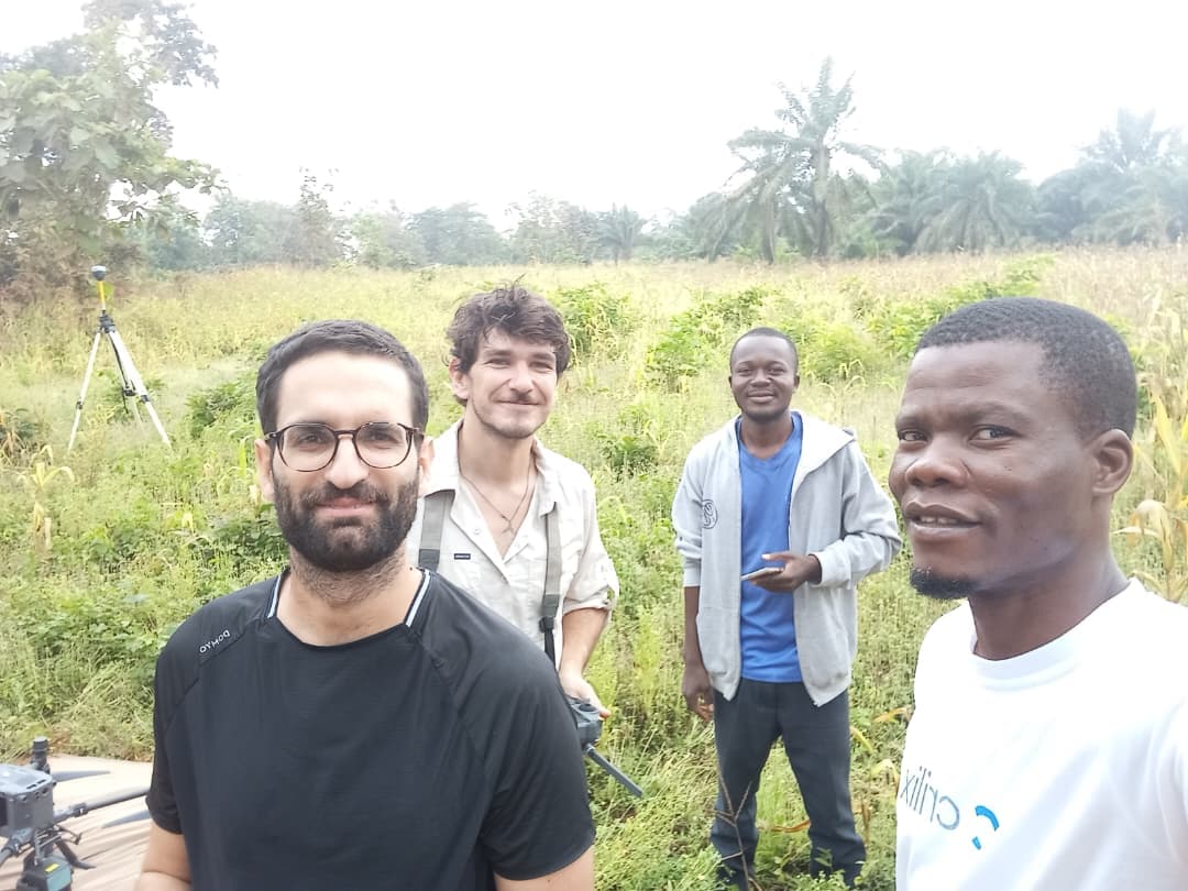Équipe OHM WORKS en mission terrain au Bénin : ingénieur photogrammétrie, télépilote drone, géomètre et opérateur — drone et trépied géomètre visibles